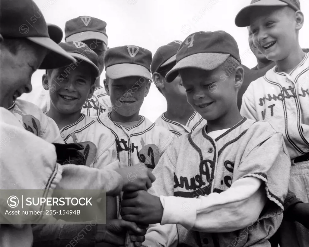 Youth league baseball team holding a baseball bat and smiling