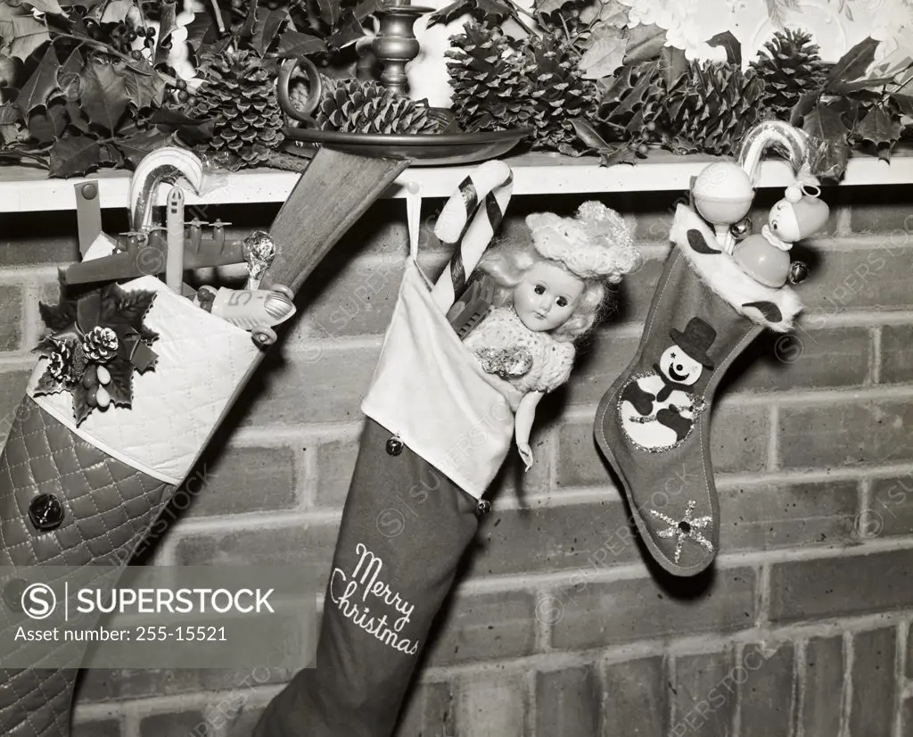 Close-up of three Christmas stockings filled with toys hanging from a mantelpiece
