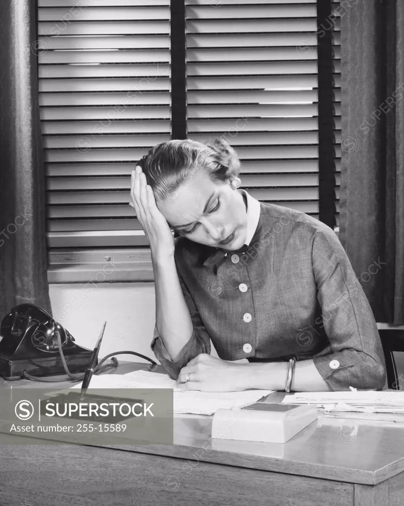 Businesswoman sitting at a desk with her head in her hands in an office