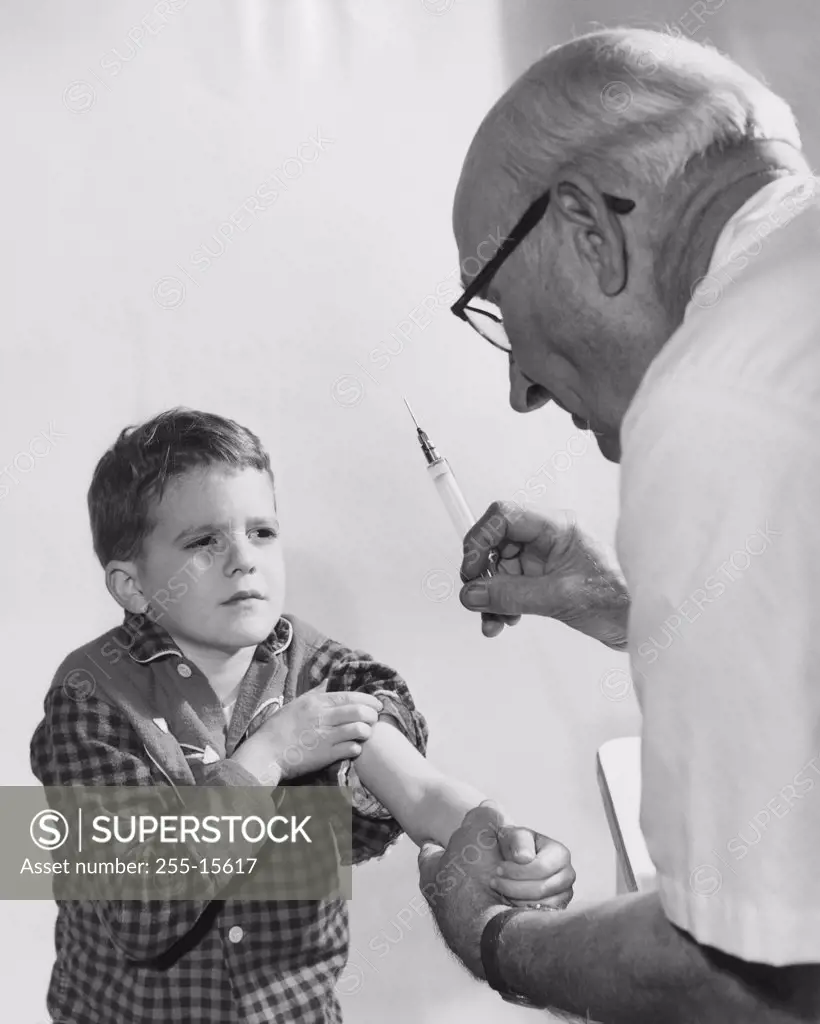 Boy getting an injection from a male doctor