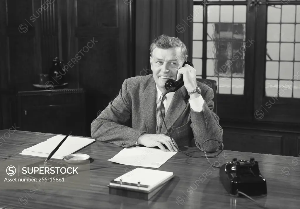 Vintage Photograph. Man in suit sitting at desk talking on telephone. Frame 5