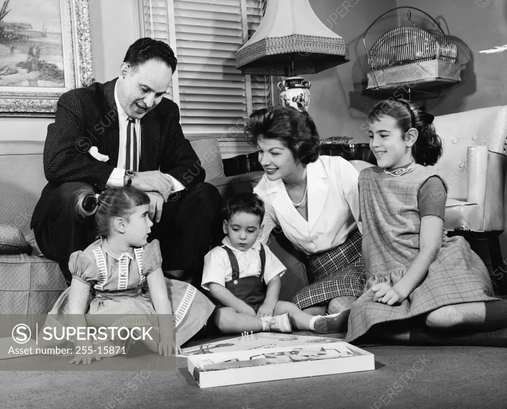 Mid adult couple with their children playing a board game