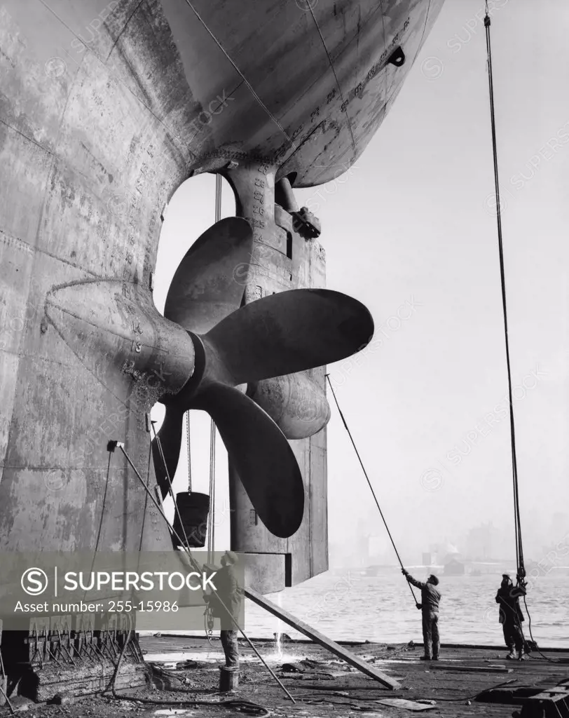 Three dock workers cleaning an industrial ship on a dry dock, Todd Shipyards Corporation, Hoboken, New Jersey, USA