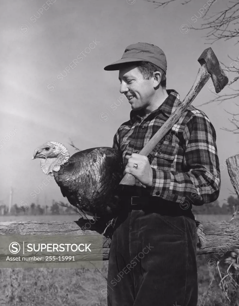 Side profile of a young man carrying a turkey and an axe