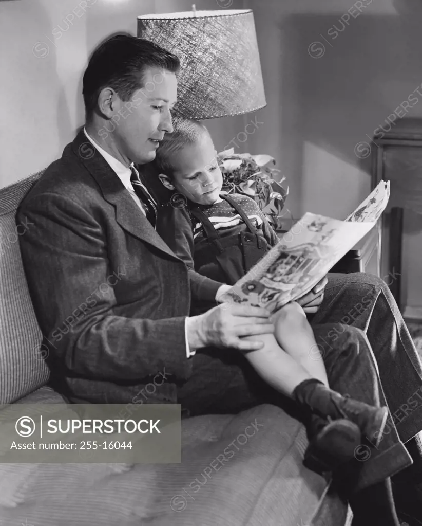 Father reading a book with his son sitting on his lap