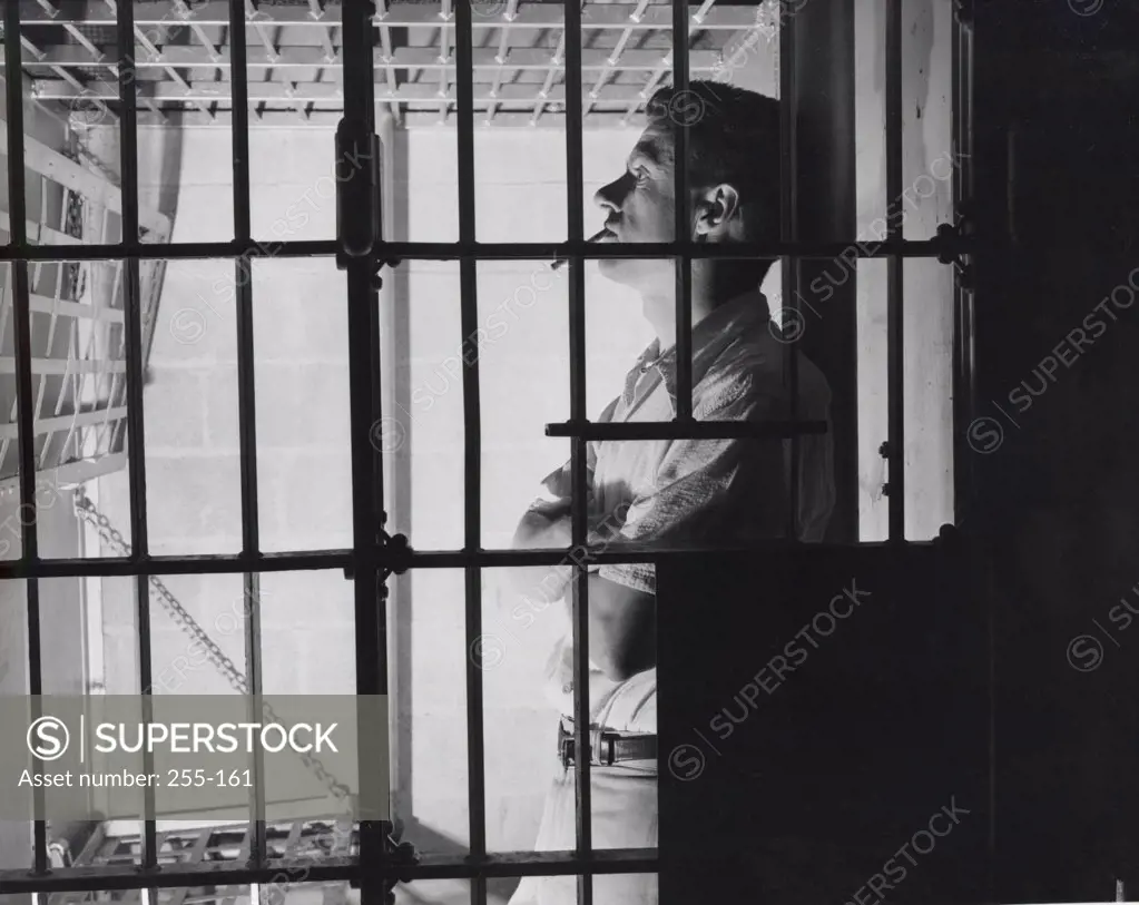 Side profile of a male prisoner smoking in a prison cell