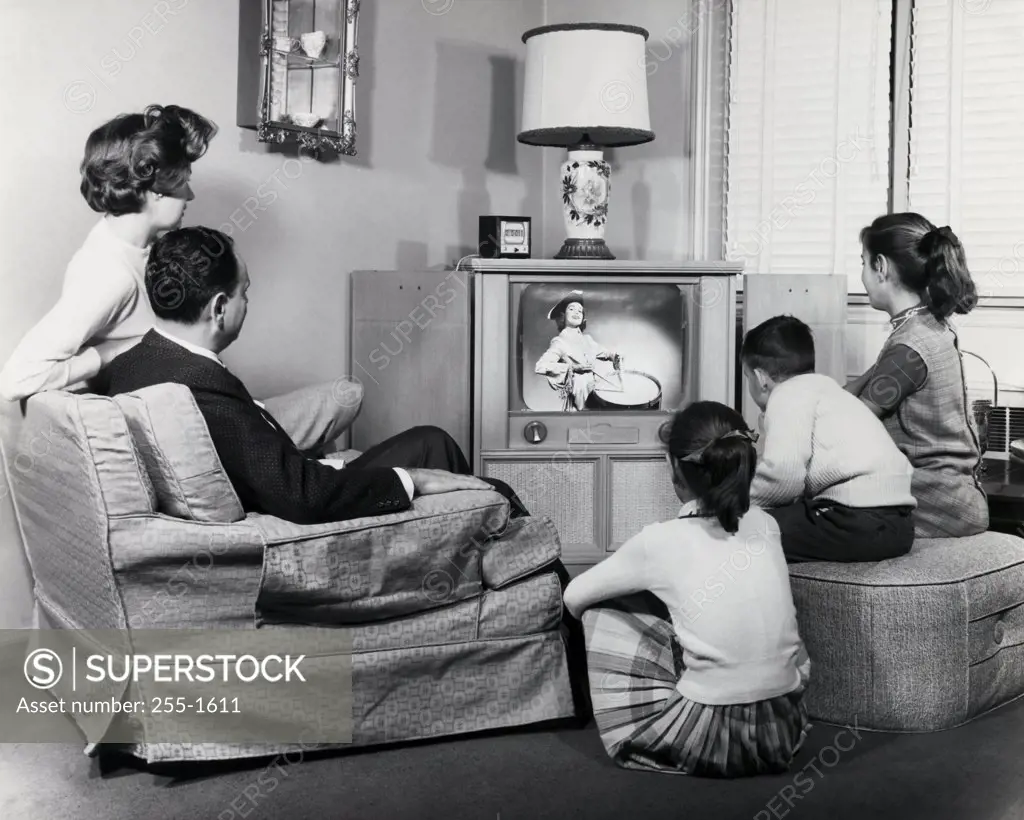 Parents with their three children watching television