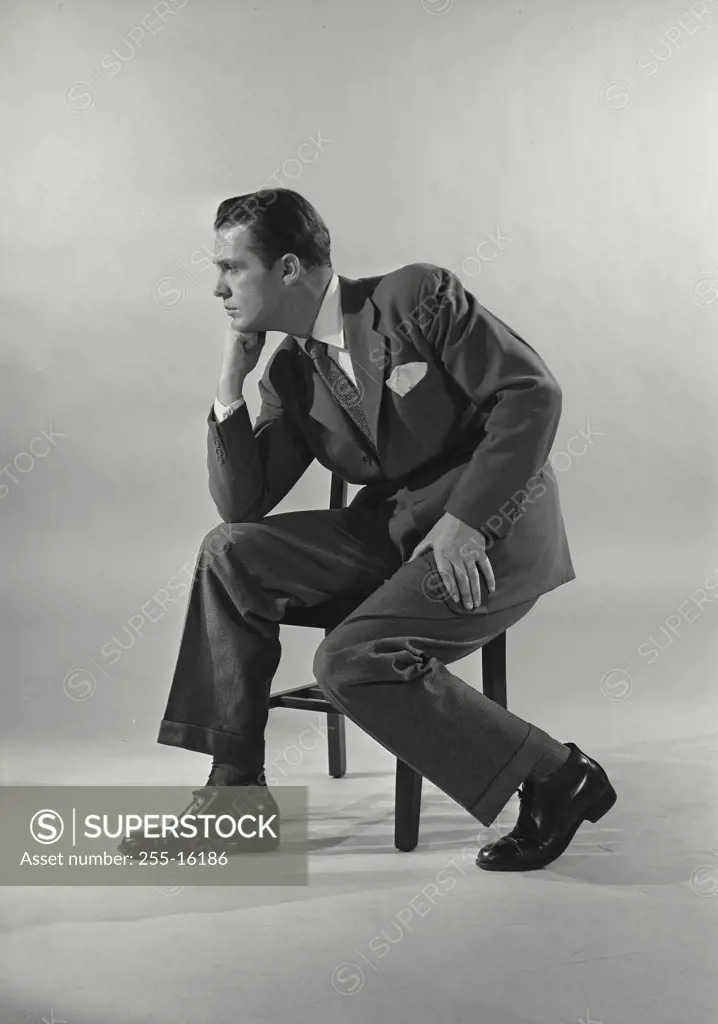 Vintage Photograph. Man in suit sittin gon chair with chin rested on fist