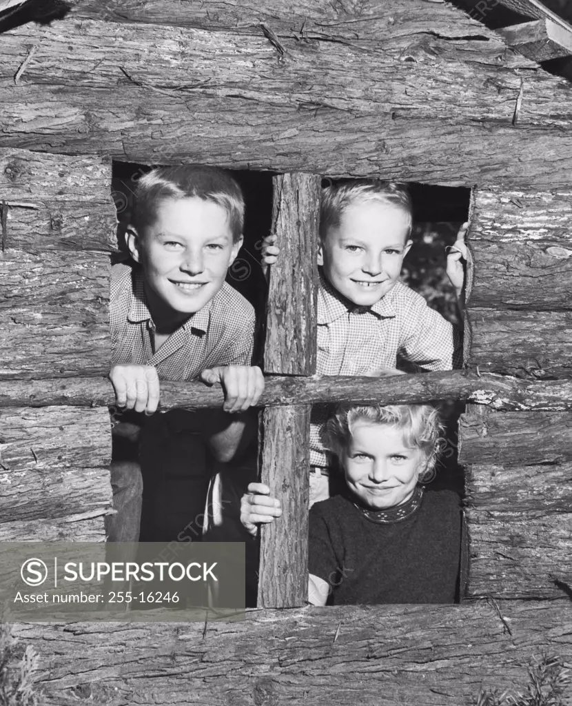 Close-up of three children looking through the window of a playhouse