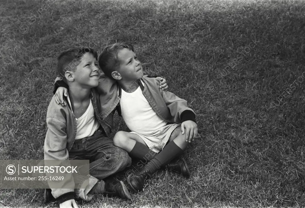 Vintage Photograph. Two boys sitting on the grass with their arms around each other