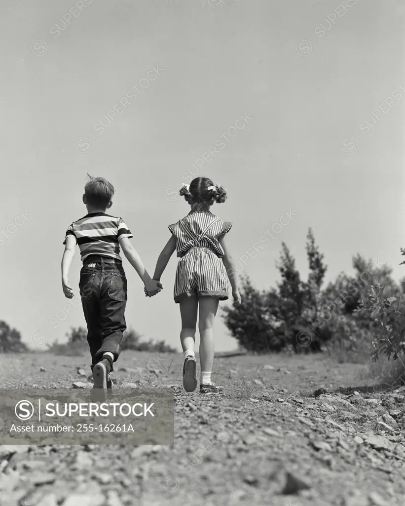 Vintage Photograph. Young boy and girl walking together on dirt road. Frame 3