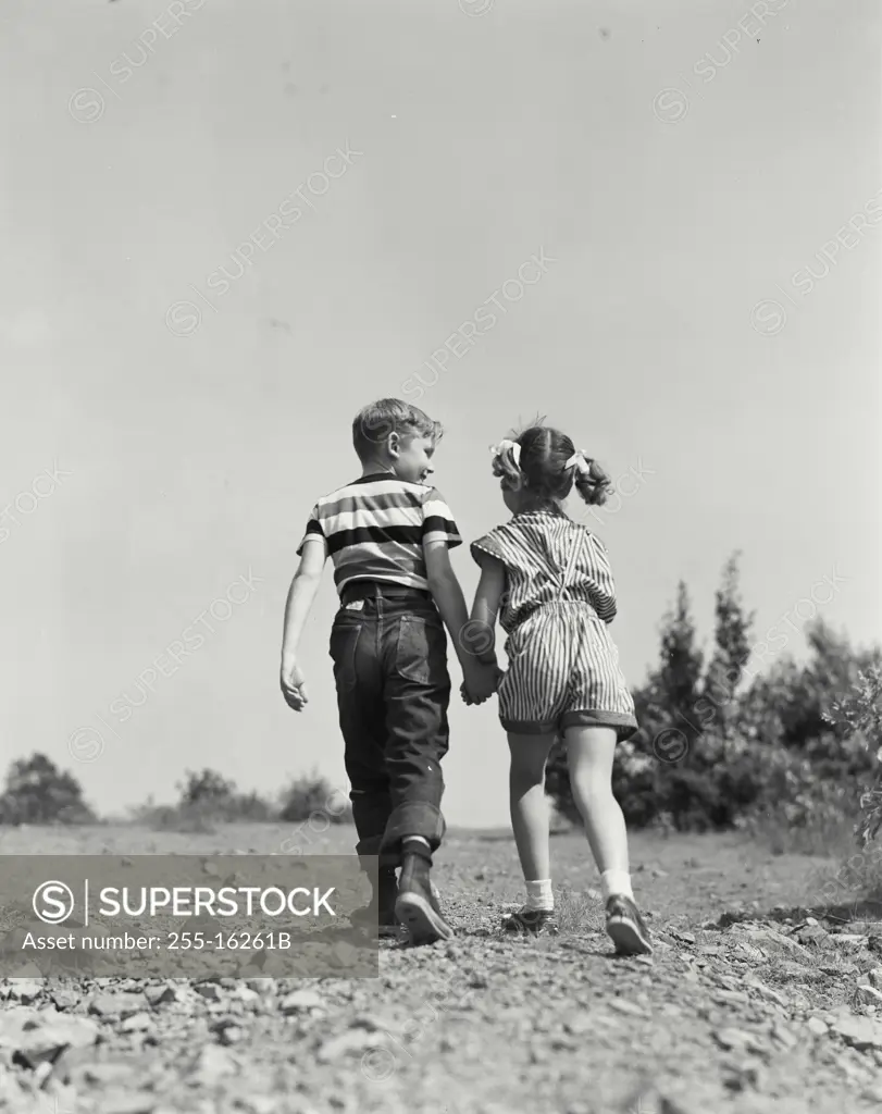 Vintage Photograph. Young boy and girl walking together on dirt road. Frame 1