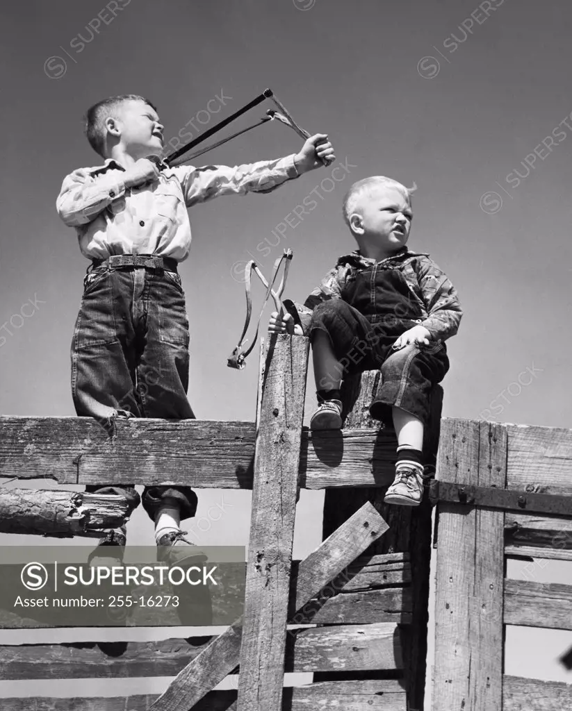 Low angle view of two boys holding slingshots