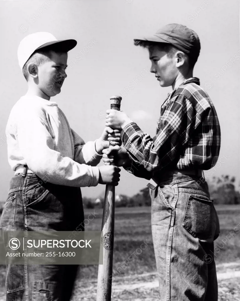 Vintage photograph of two boys wearing baseball caps, gripping baseball club
