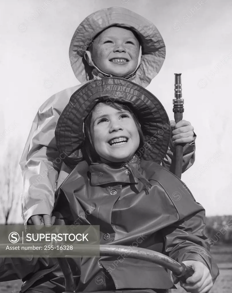 Close-up of a girl and her brother wearing raincoats and smiling