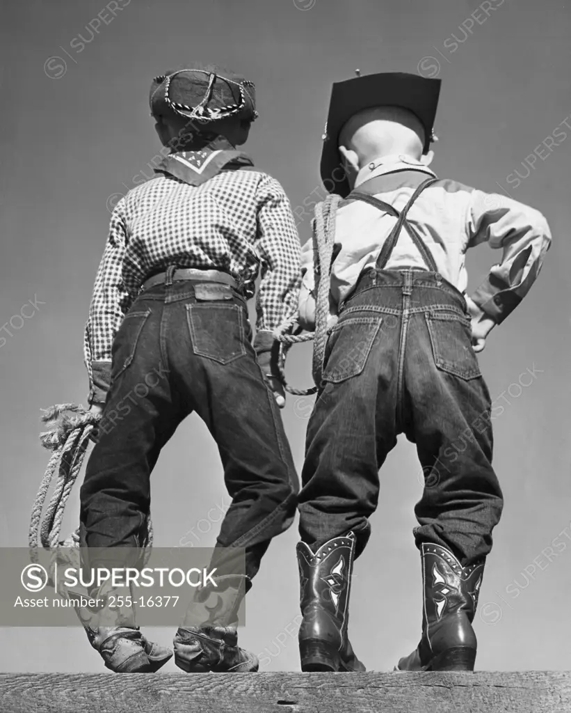 Rear view of two boys in cowboy costumes