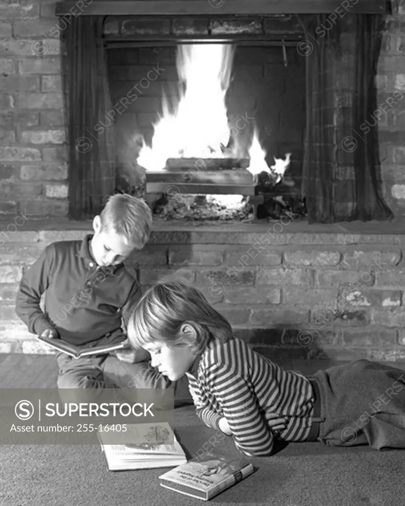 Boy and girl reading books in front of fireplace