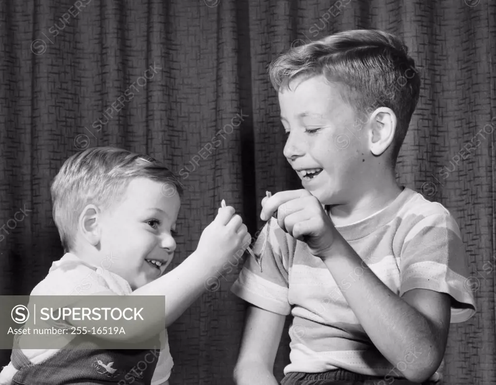 Two boys pulling a wishbone and smiling