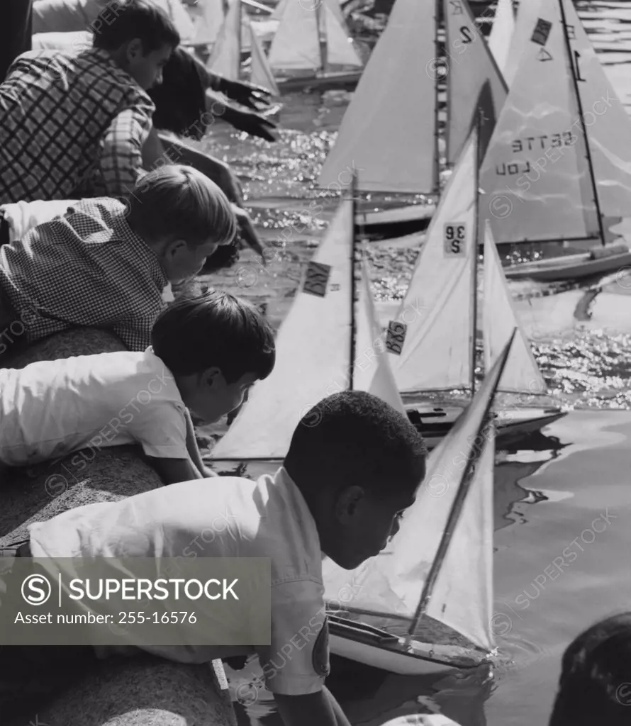 Group of children placing their toy boats in water for a race