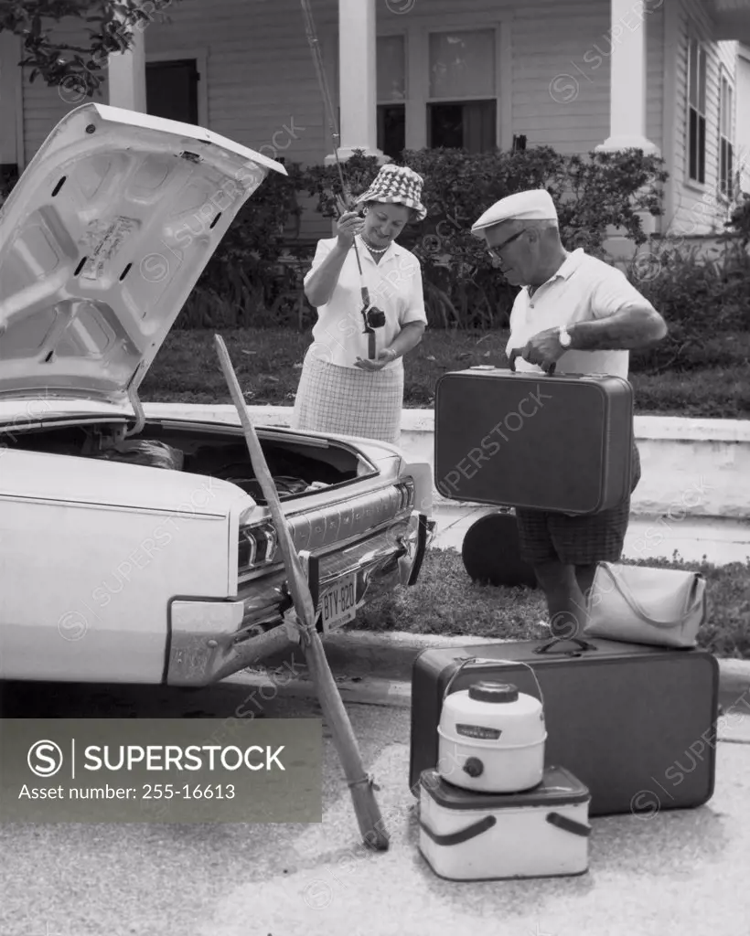 Senior couple loading luggage into a car trunk