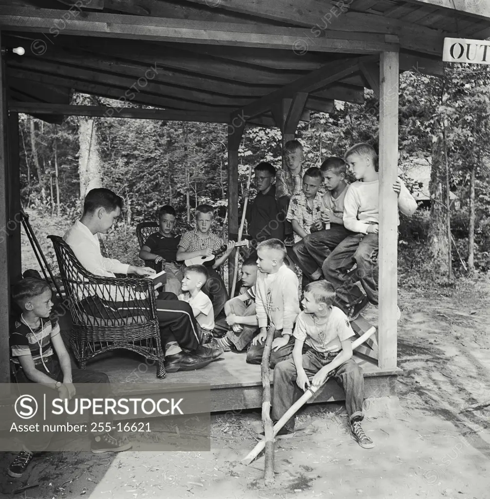 Vintage Photograph. Teacher sitting with his students on a porch and reading a book