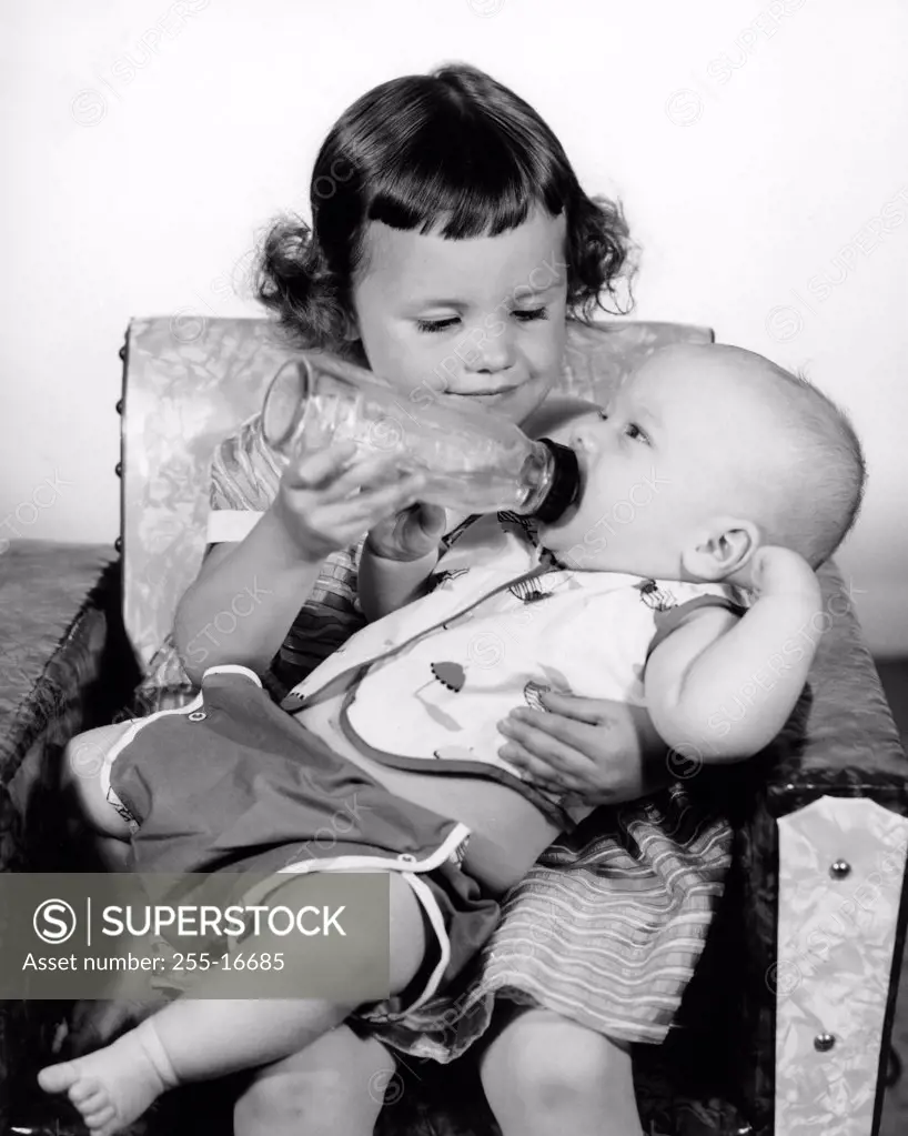 Girl feeding baby brother with dummy