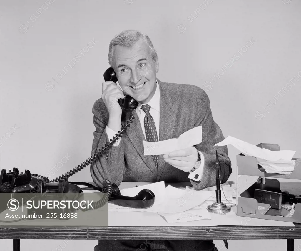 Businessman holding a check and talking on the telephone