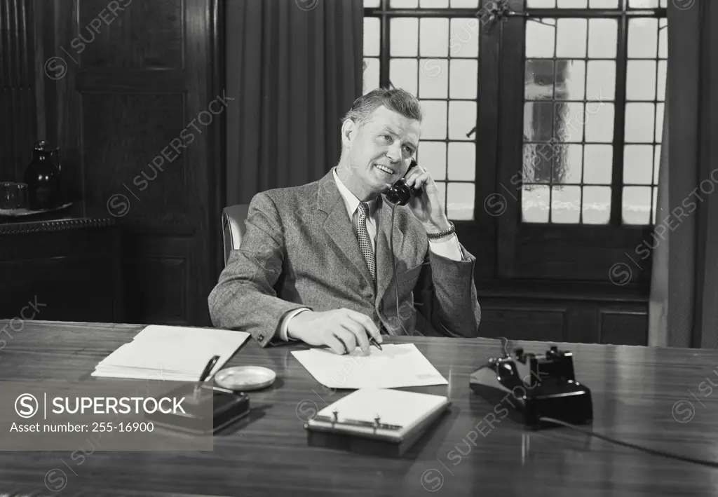 Vintage Photograph. Man in suit sitting at desk talking on telephone. Frame 6