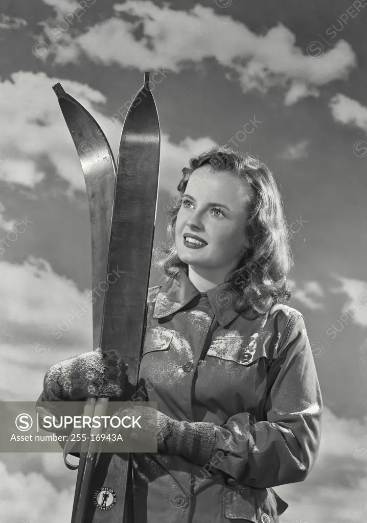 Vintage Photograph. Portrait of young woman holding skis and smiling