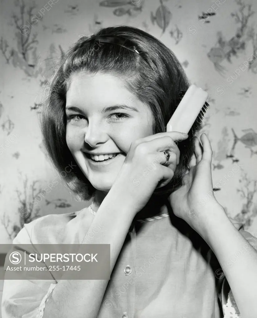 Portrait of a teenage girl brushing her hair and smiling, 1966