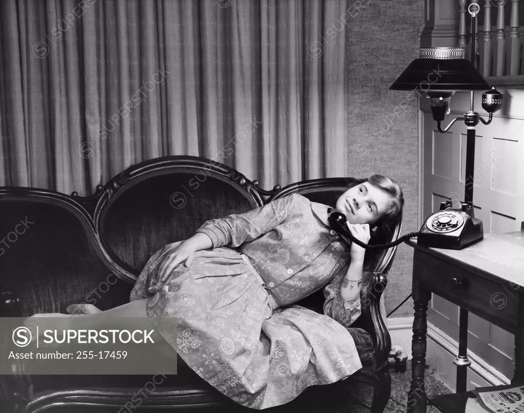 Teenage girl lying on a couch and talking on the telephone