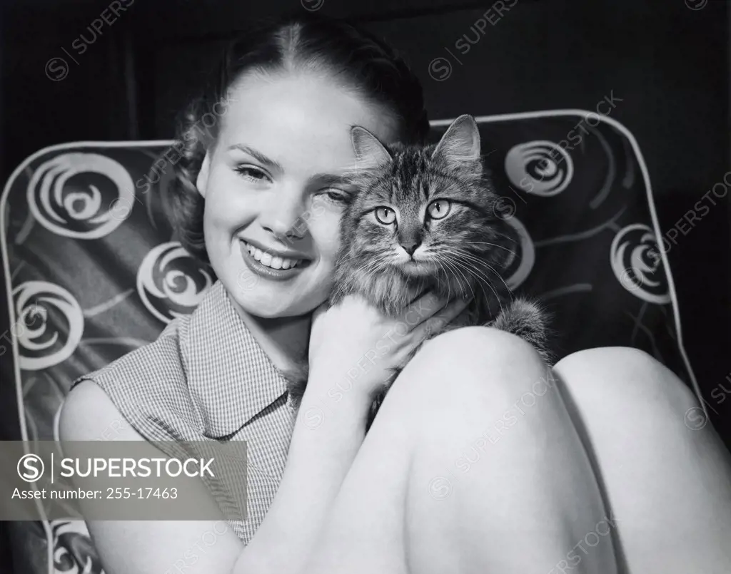 Close-up of a teenage girl hugging a cat and smiling