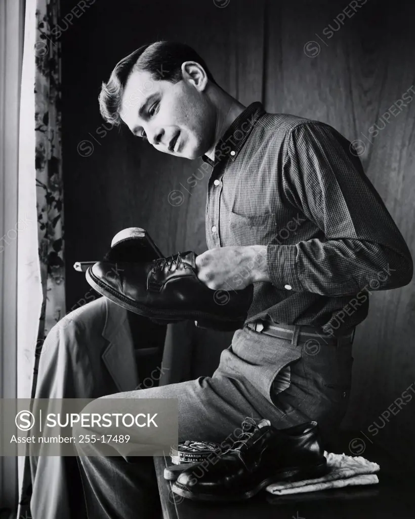 Side profile of a teenage boy polishing his shoes