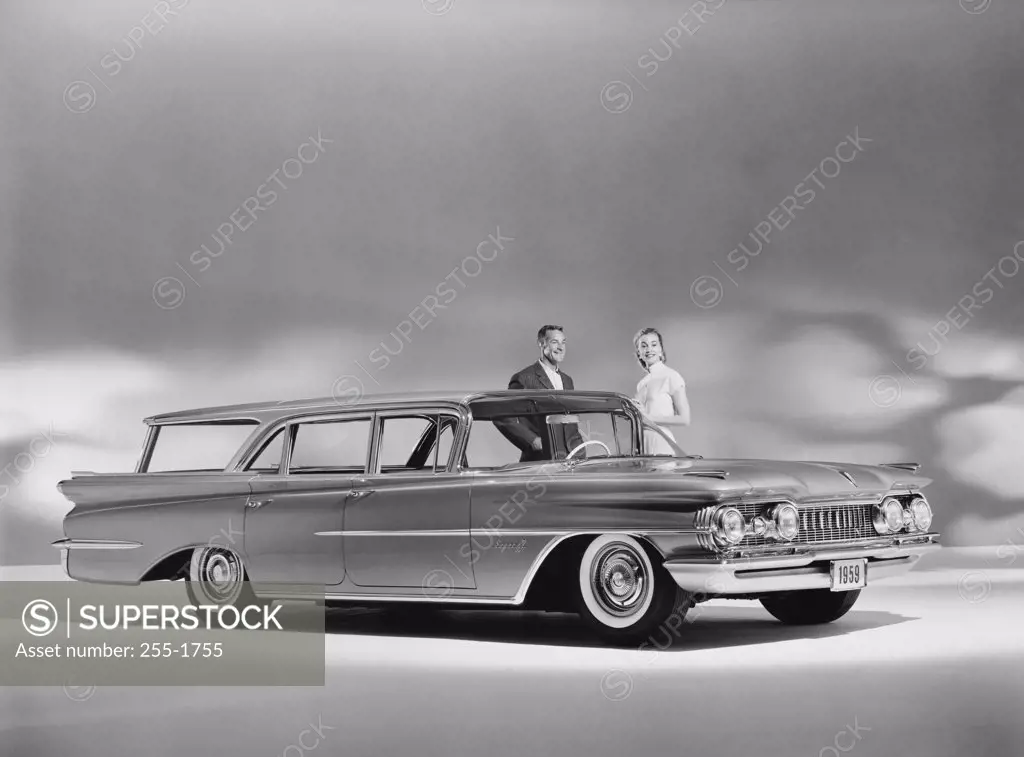 Man and a woman standing near a 1959 Oldsmobile Super 88 Fiesta