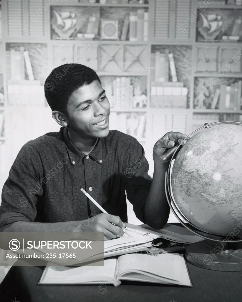 Close-up of a teenage boy searching a desktop globe on the table