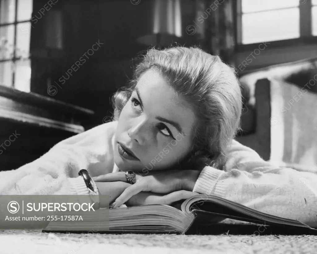 Close-up of a teenage girl lying on a book and thinking