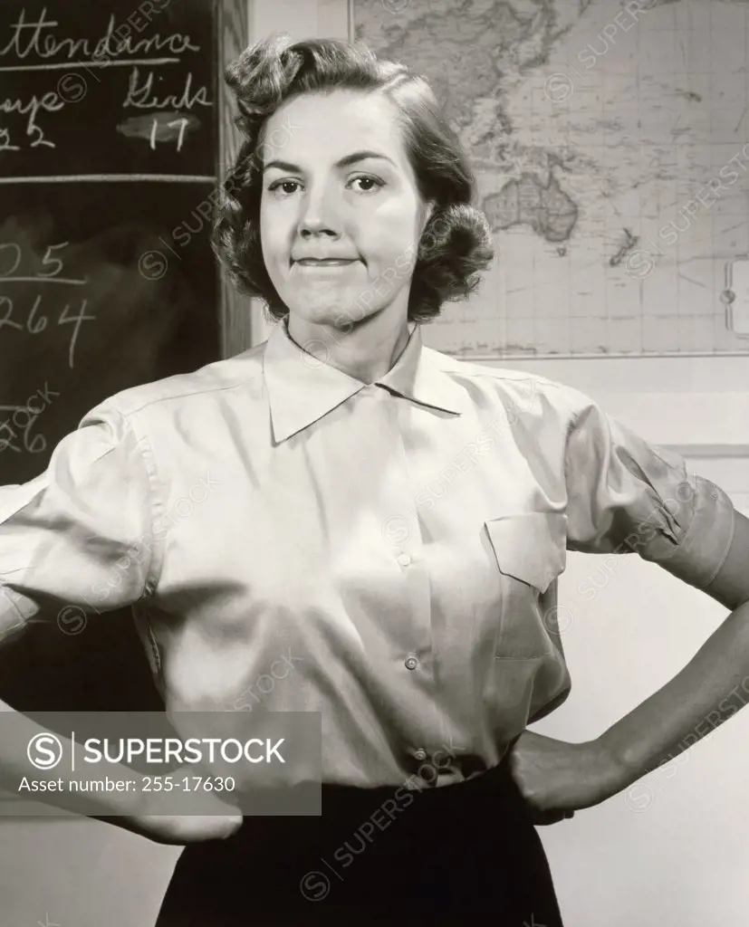 Portrait of a female teacher with arms akimbo in a classroom