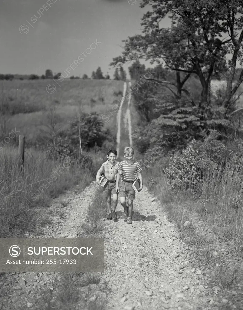 Vintage Photograph. Two young boys walking up the trail with school packs