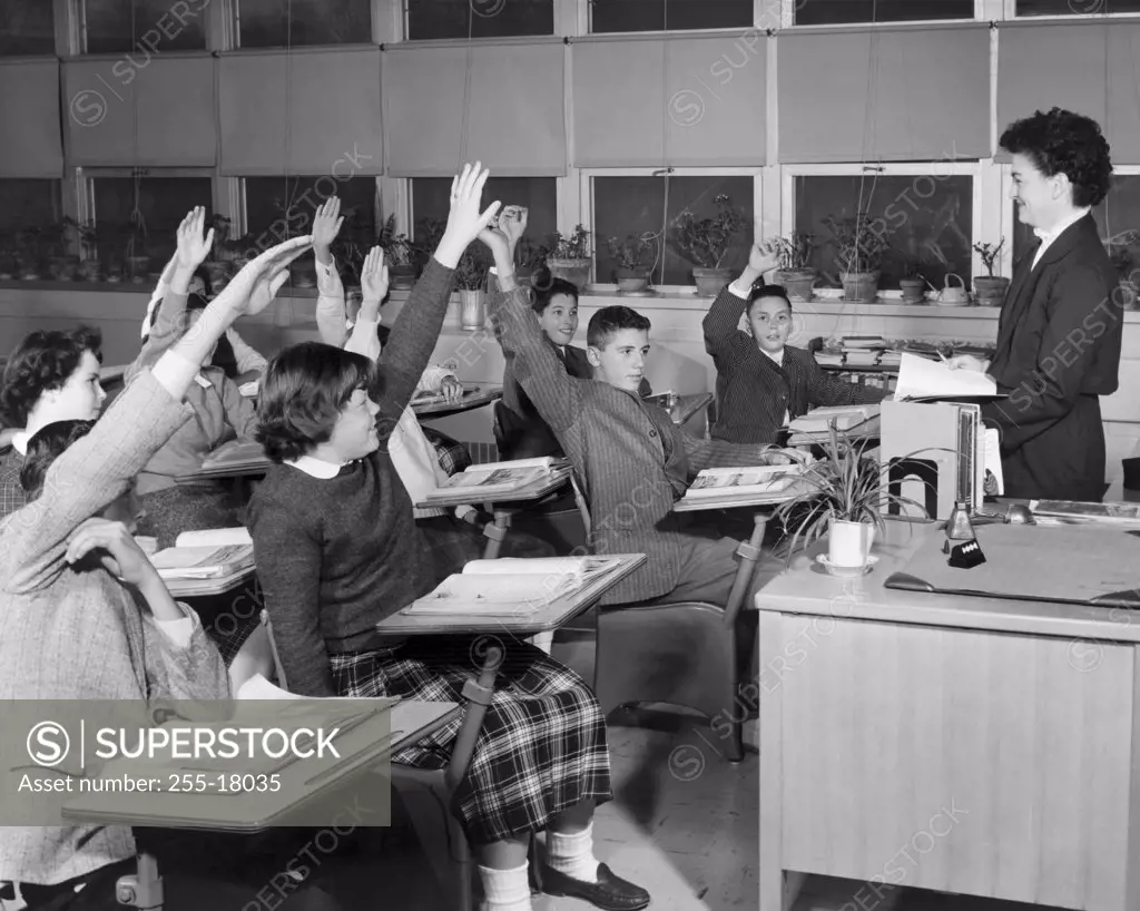 Group of students raising their hands in a classroom