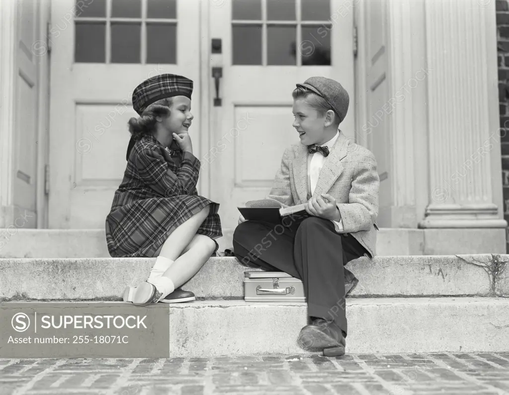 Vintage Photograph. Young boy and girl at top of steps with school supplies. Frame 4