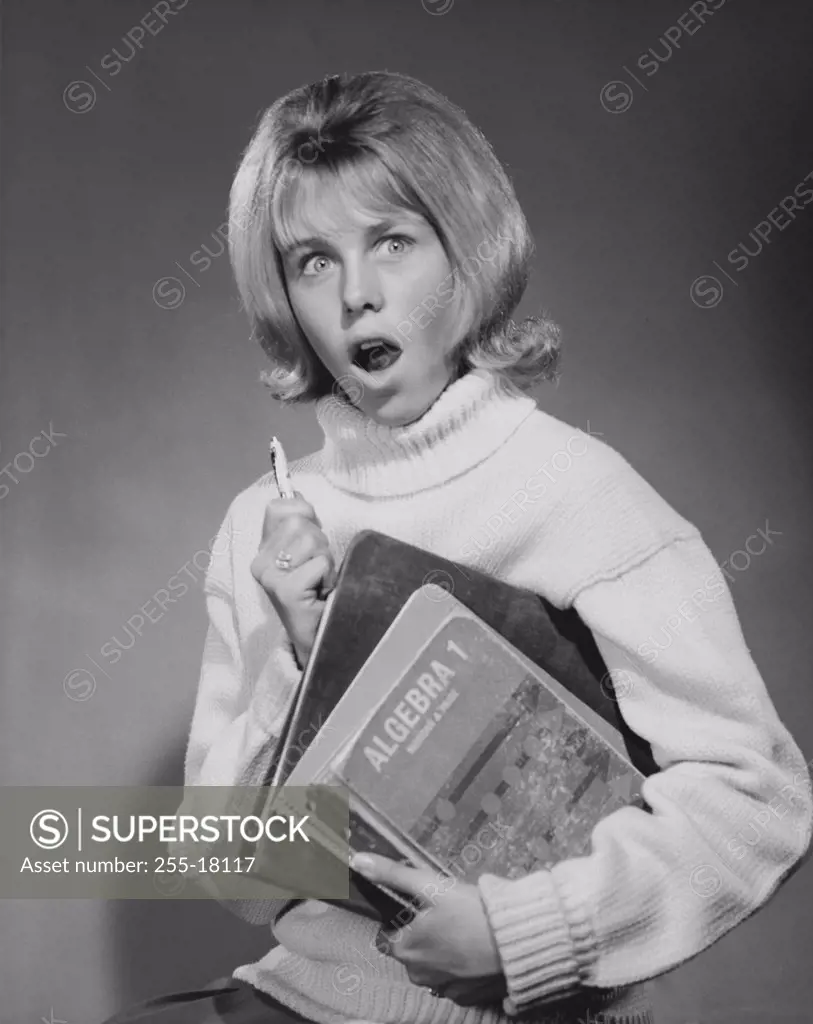 Teenage girl holding books and looking surprised