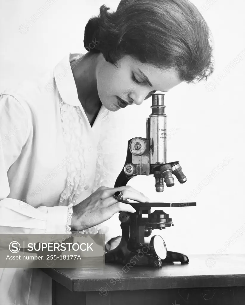 Teenage girl looking through a microscope