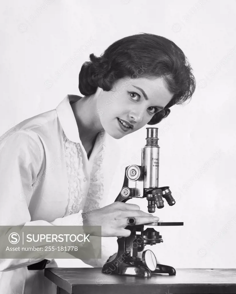 Teenage girl standing near a microscope