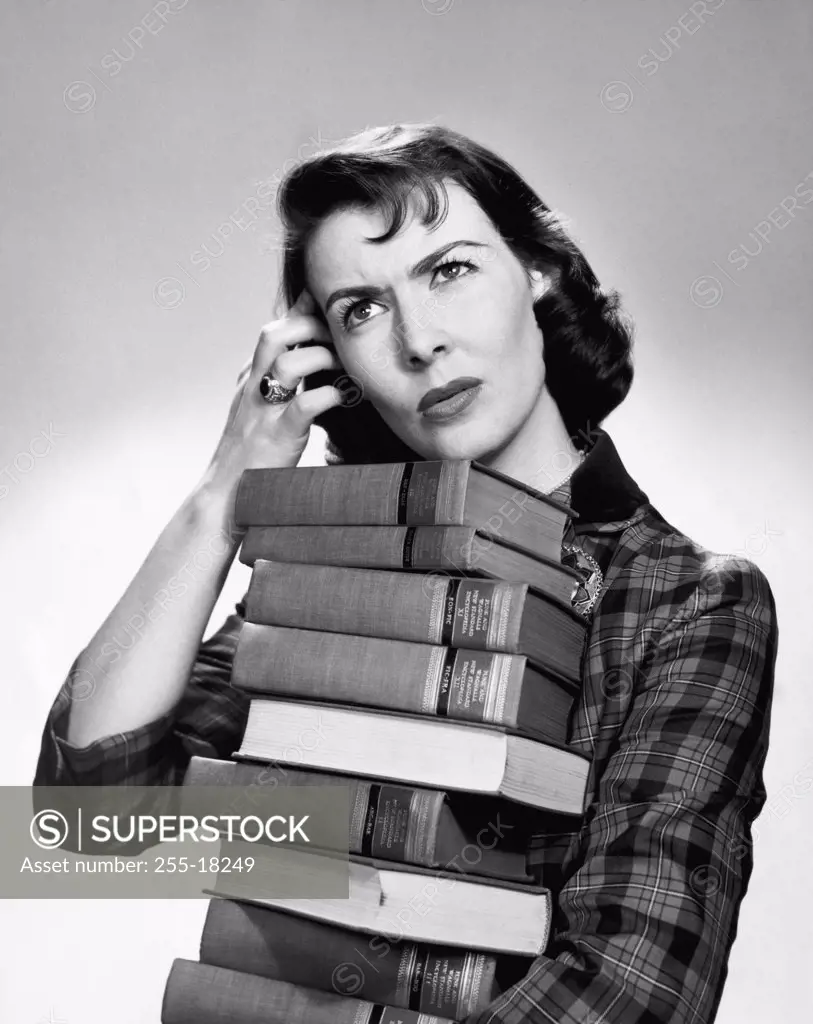 Close-up of a mid adult woman carrying a stack of books