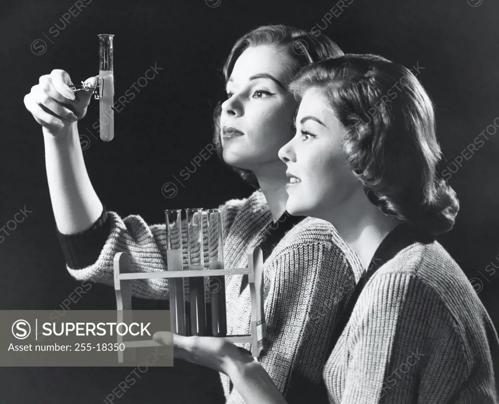 Two young women examining a solution in a test tube