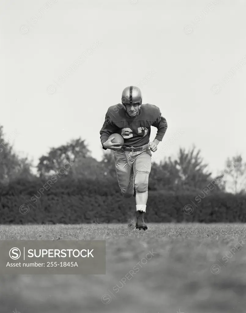 Vintage Photograph. Football player running with ball in field
