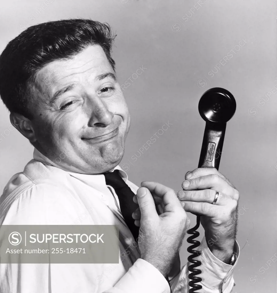 Side profile of a businessman holding a telephone receiver making a face