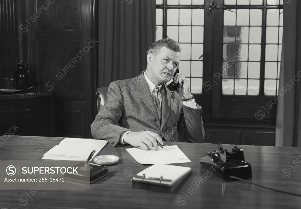 Vintage Photograph. Man in suit sitting at desk talking on telephone. Frame 7