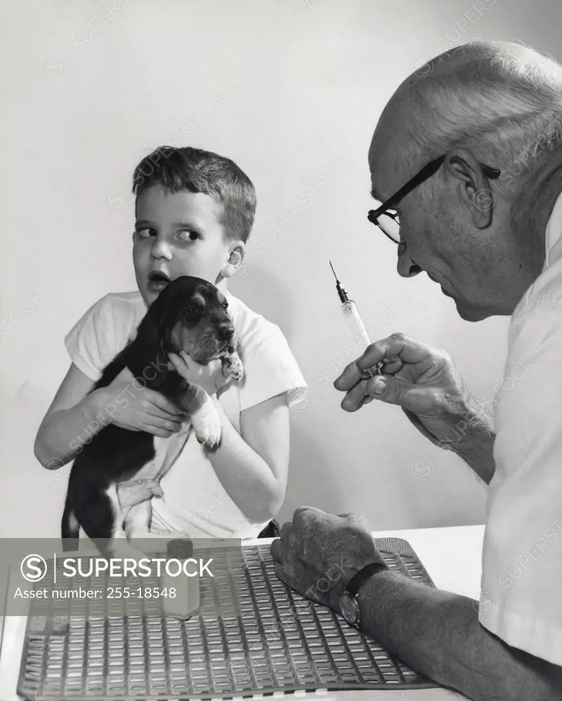 Veterinarian holding a syringe and a boy holding his puppy