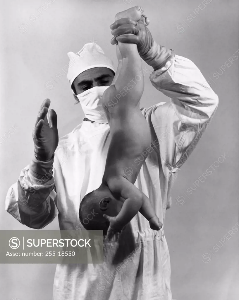 Male doctor spanking a baby upside down